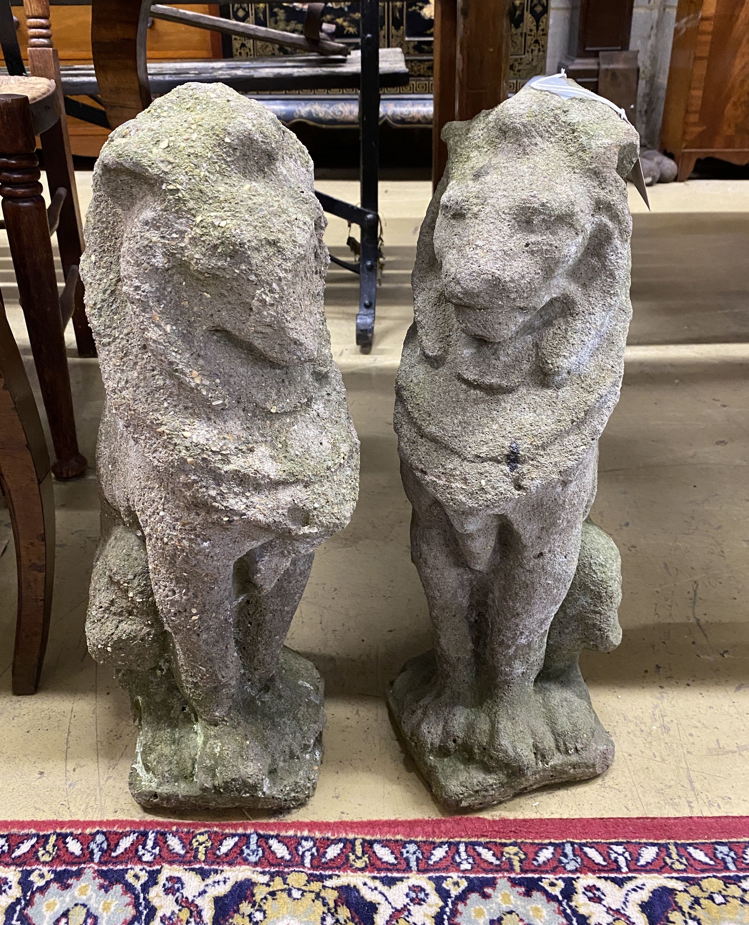 A pair of reconstituted stone seated lion garden ornaments, height 52cm